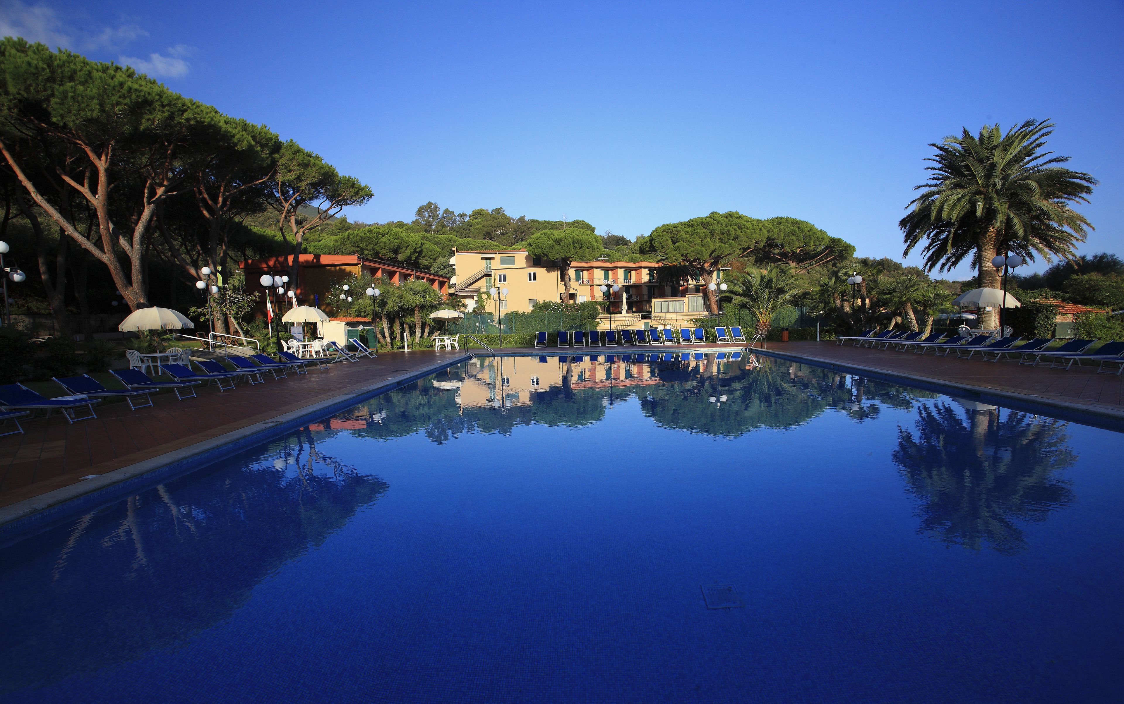 Una piscina al aire libre, sombrillas, sillones reclinables de piscina