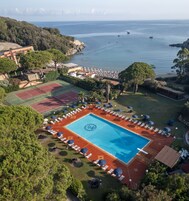 Una piscina al aire libre, sombrillas, sillones reclinables de piscina