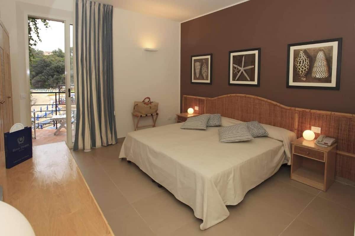 A bedroom with a bed, bedside tables, a suitcase, and framed pictures on the wall.