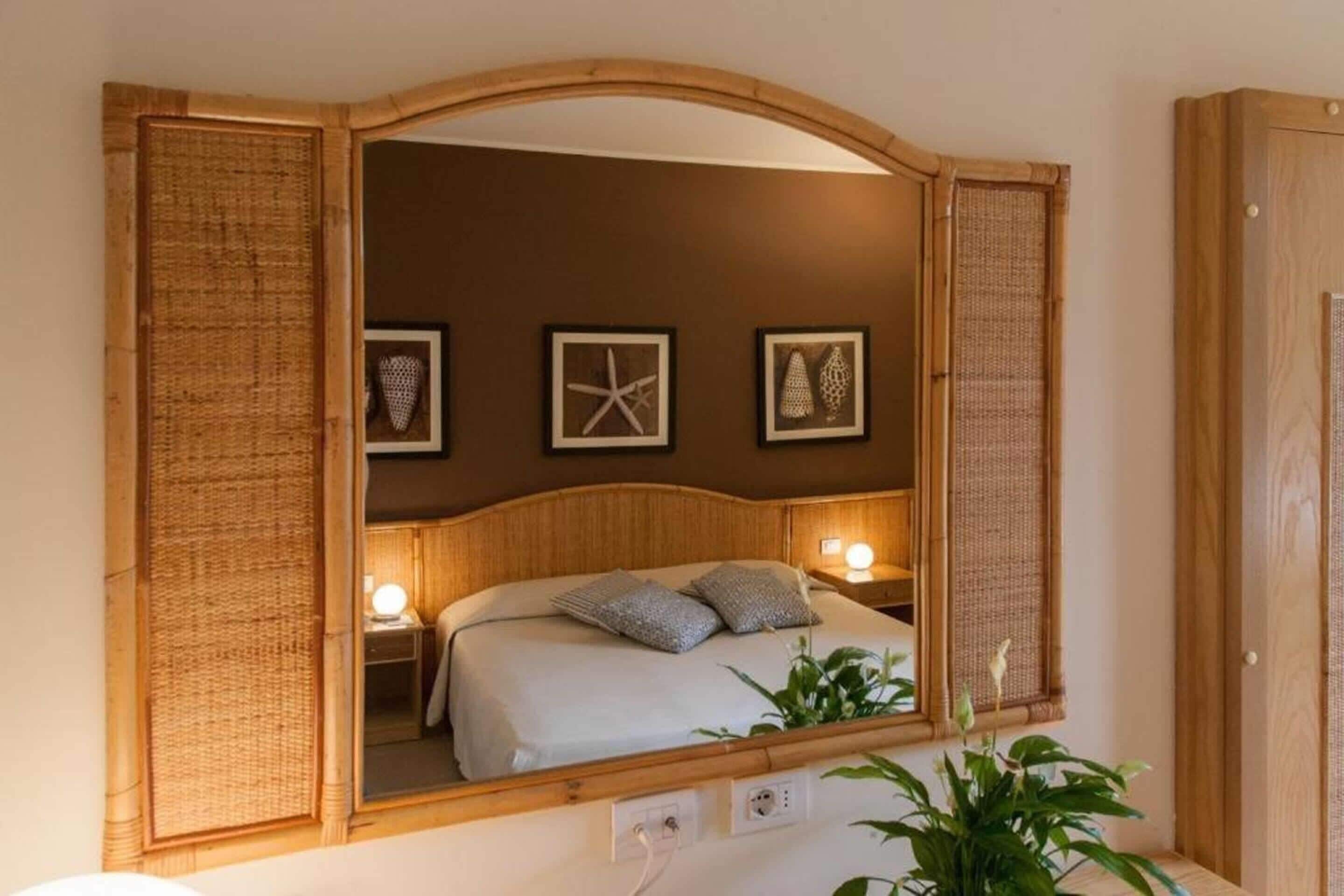 A room with a bed, bedside lamps, and framed artwork on the wall.