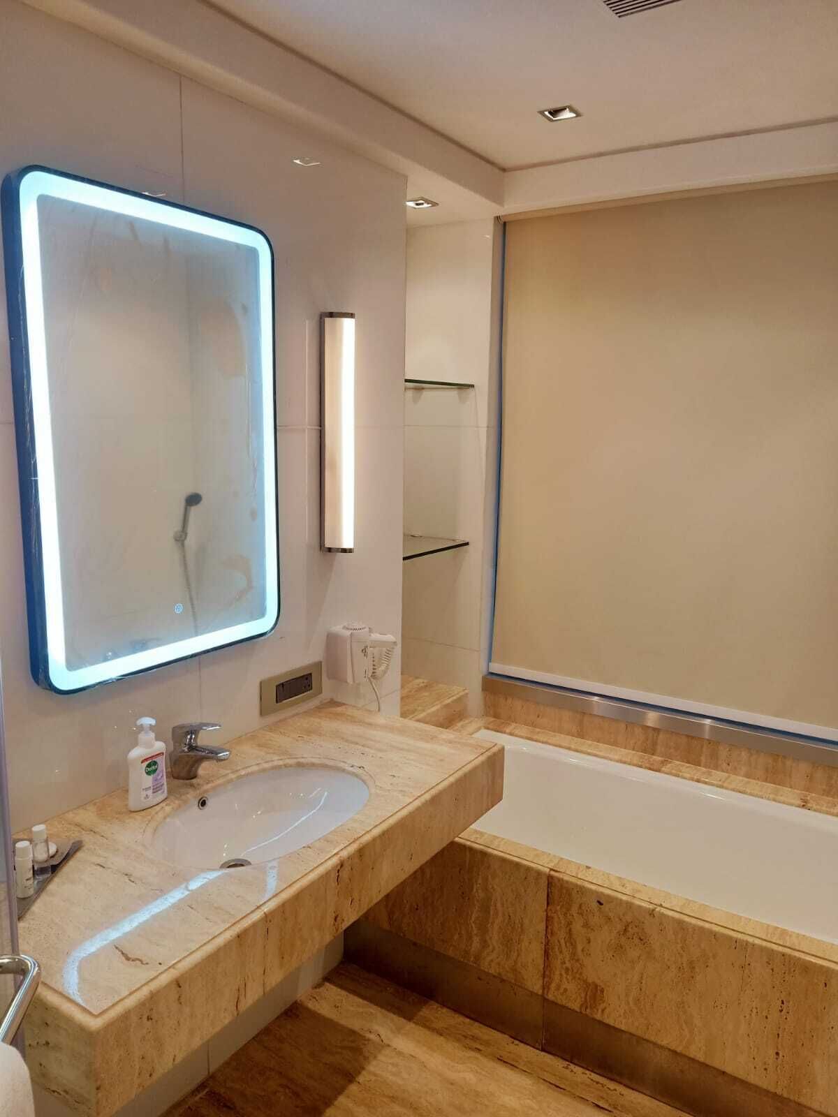 Un baño moderno con un espejo grande, un lavamanos y una bañera.