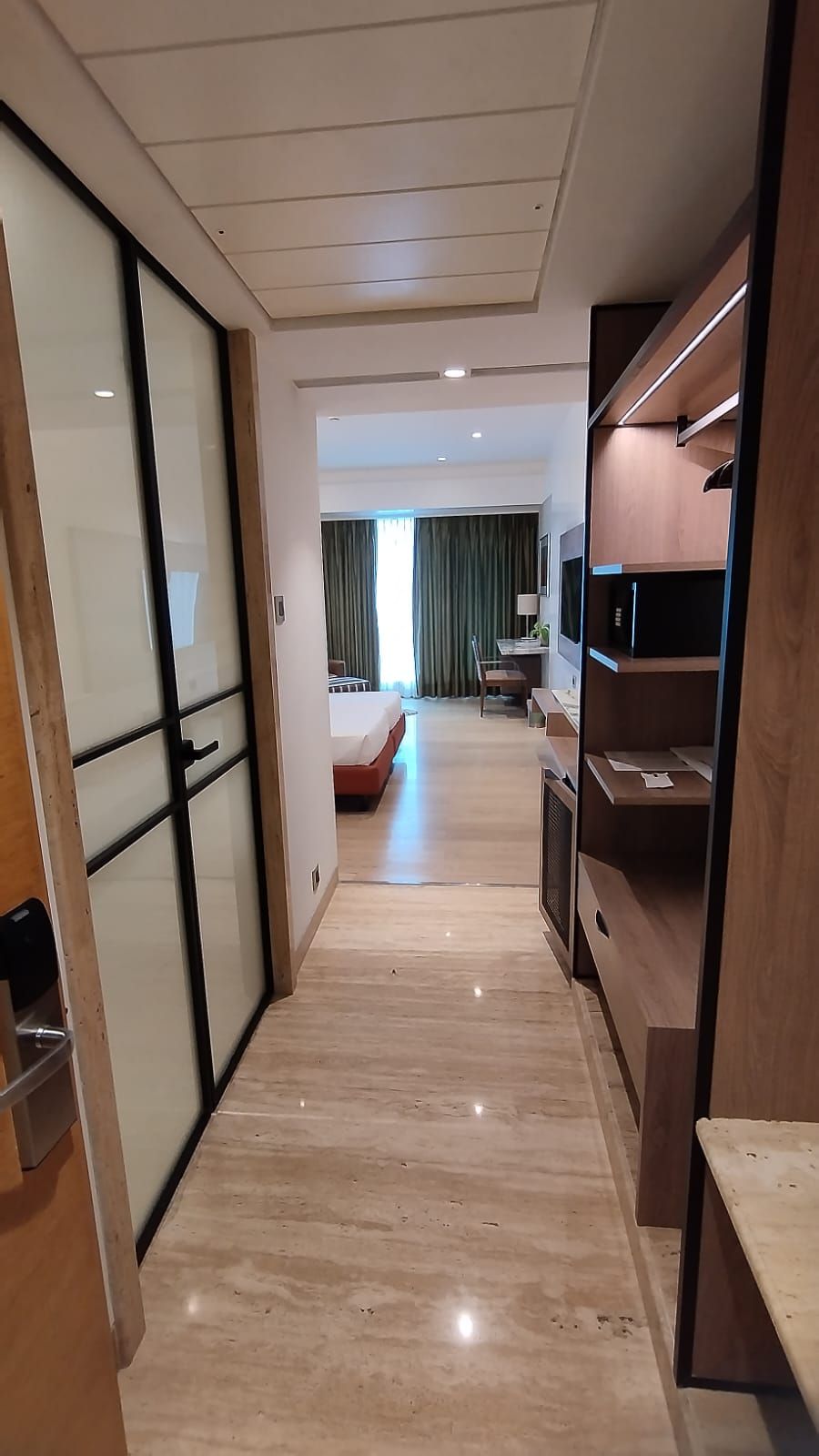 A hotel room with a bed, a desk, a TV, and a sliding door.