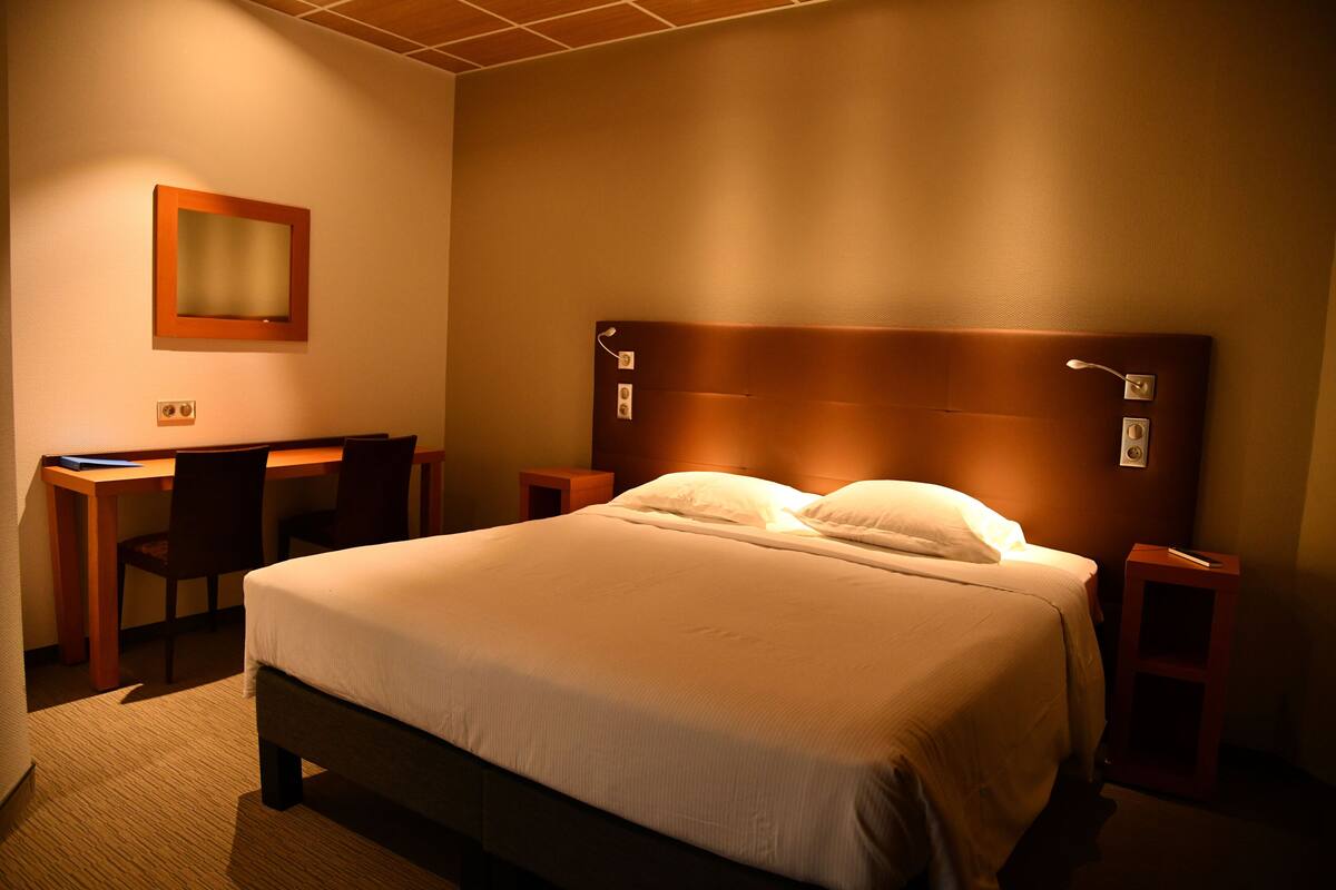 Una habitación de hotel con cama, escritorio y silla.