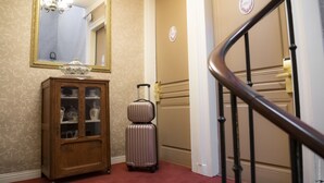 A hallway with a wooden cabinet, a suitcase, and a mirror.