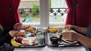 A dining table with trays of food, including bread, cheese, and fruit.