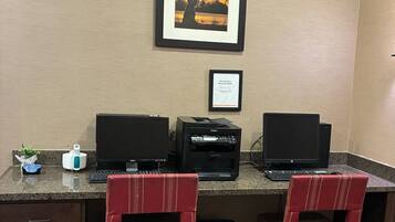 A workspace with two desks, two chairs, two monitors, a printer, and a framed picture on the wall.