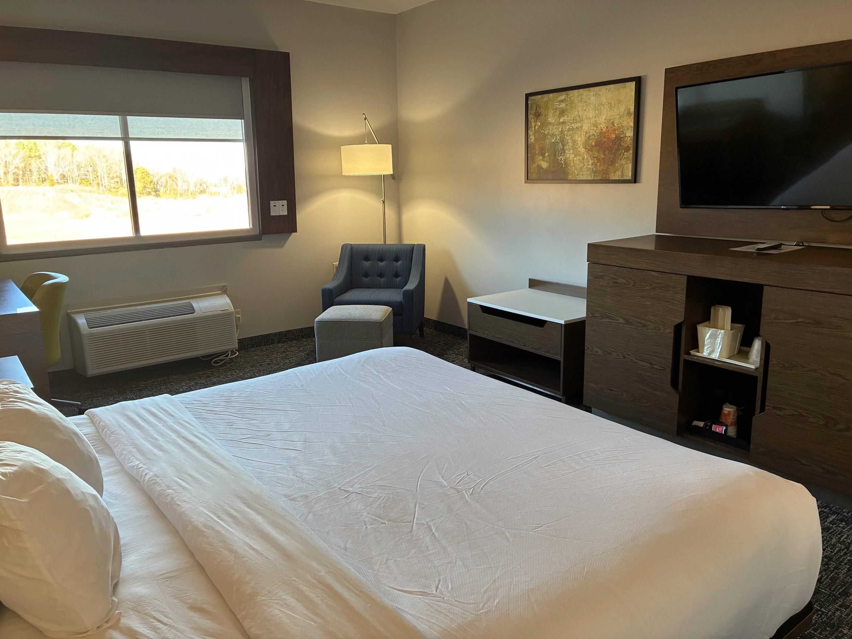A hotel room with a bed, a desk, a chair, a TV, and a window with a view.