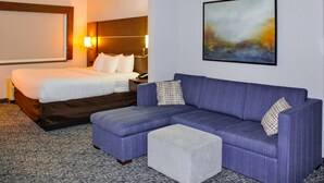 Una habitación de hotel con cama, sofá y un pequeño otoman.
