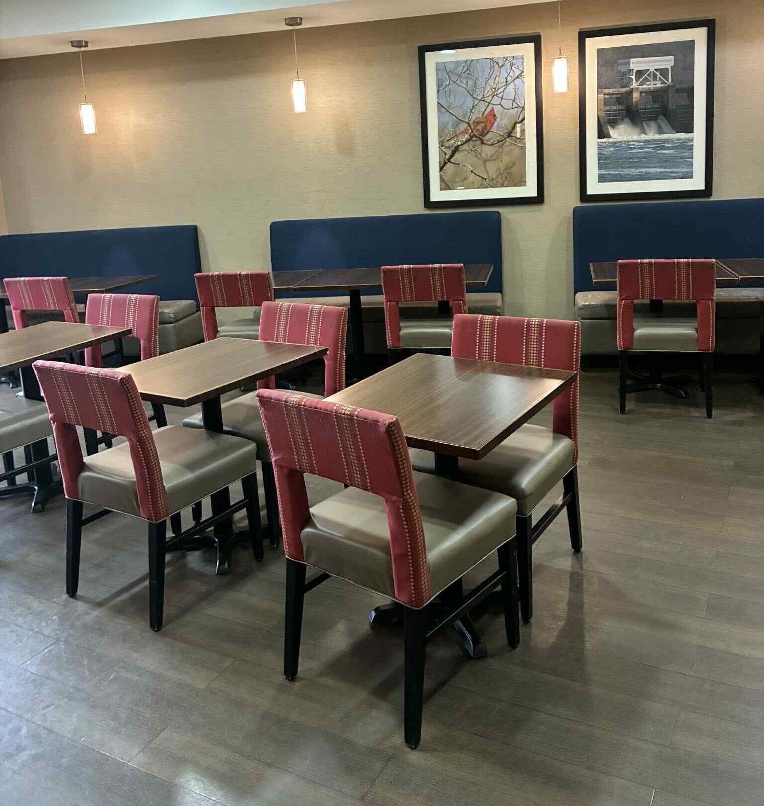 A restaurant with booths and tables, featuring artwork on the walls and pendant lighting.
