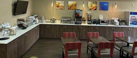 Une cuisine moderne dotée d’un îlot central, d’un coin café et d’un espace détente avec des chaises à revêtement rouge.
