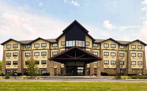 Un hotel a più piani con un ingresso ben visibile e un ampio parcheggio antistante.