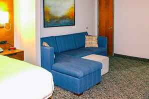 Relax in comfort with a sofa, ottoman, and vibrant artwork in this inviting space.