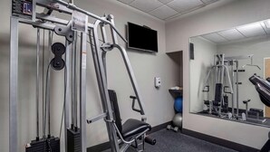 Une salle de sport équipée de matériel d’exercice, d’un téléviseur et d’un miroir.