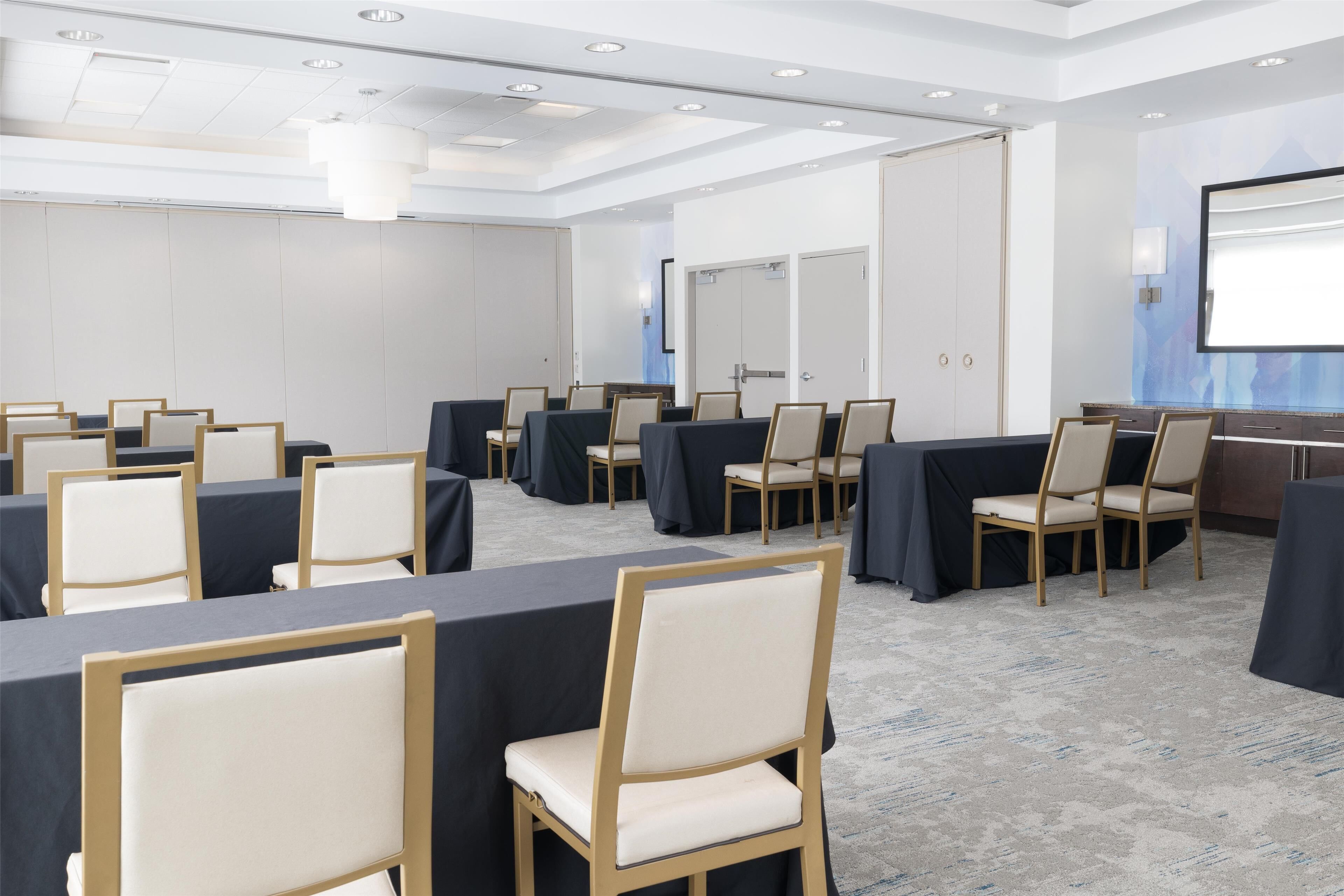 A conference room with tables and chairs, a projector screen, and a door.