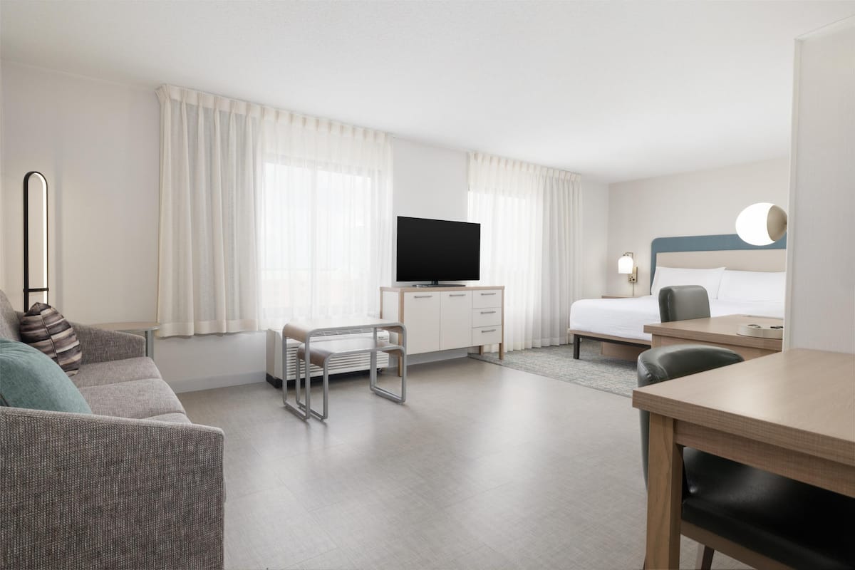 Une chambre d’hôtel comprenant un lit, un bureau, une télévision, un canapé et une table à manger.