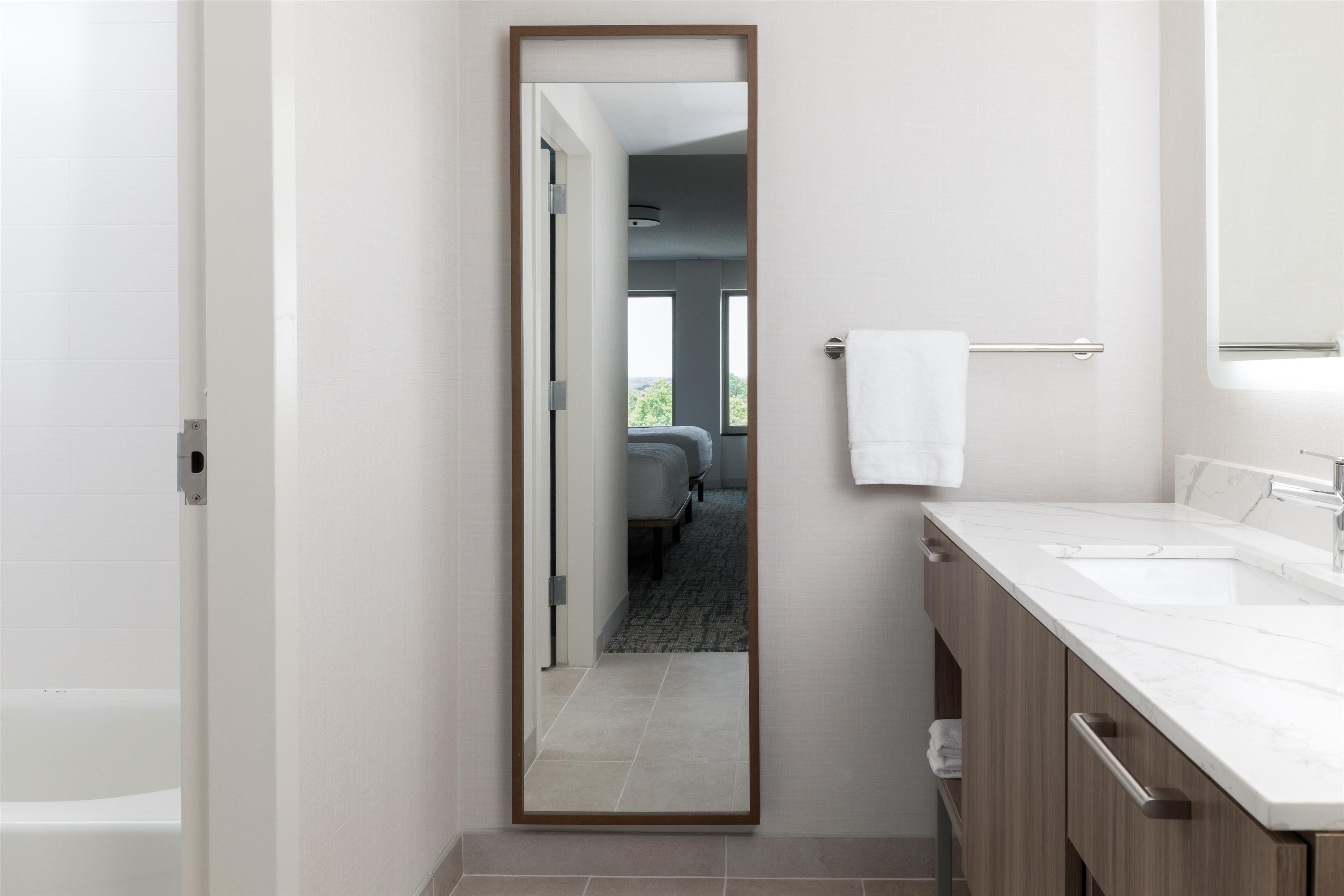A modern bathroom with a large mirror, two sinks, and a towel rack.