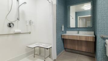 Un baño moderno con ducha, tocador con espejo y retrete.