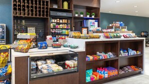 A grocery store interior with a variety of products on shelves and in bins, a refrigerated section, and a display area with snacks and beverages.
