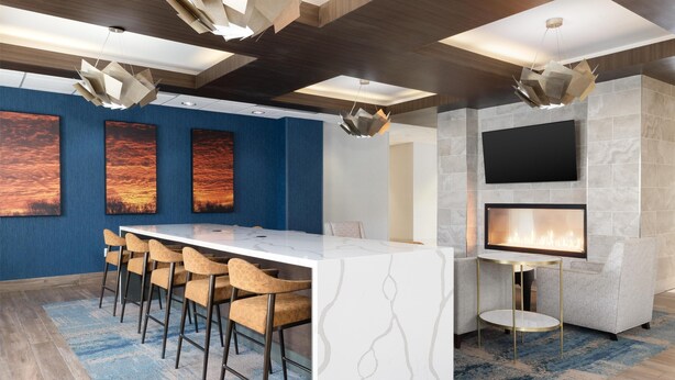 A modern living room with a white marble bar, a flat-screen TV, and a fireplace.