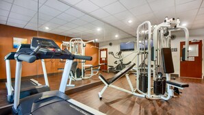 Une salle de sport équipée de tapis de course, d’appareils de musculation et d’un mur recouvert de miroirs.