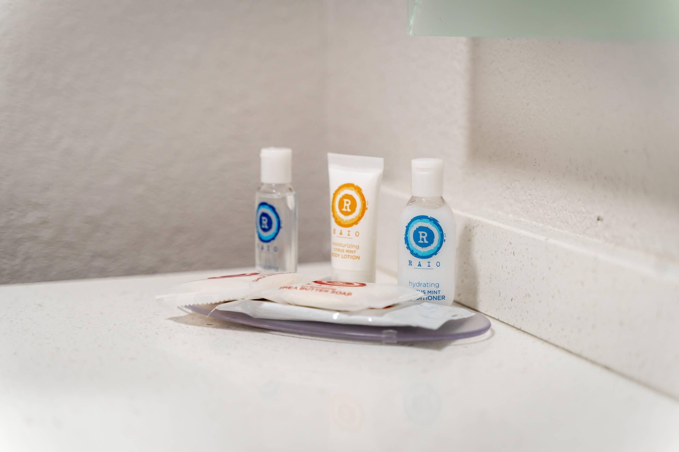Artículos de aseo en una encimera de baño, como una crema hidratante corporal, jabón de manos y gel antibacterial.