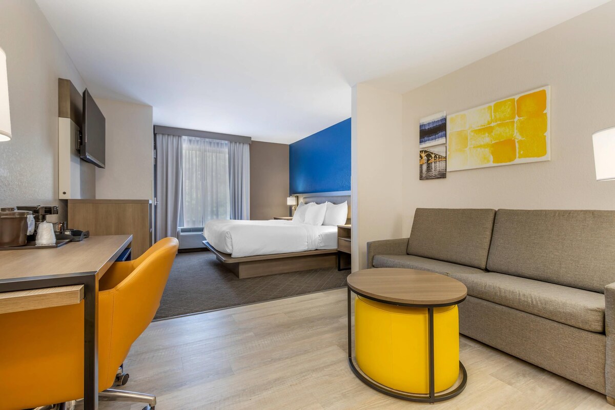 A hotel room with a bed, a sofa, a desk, and a small round table.