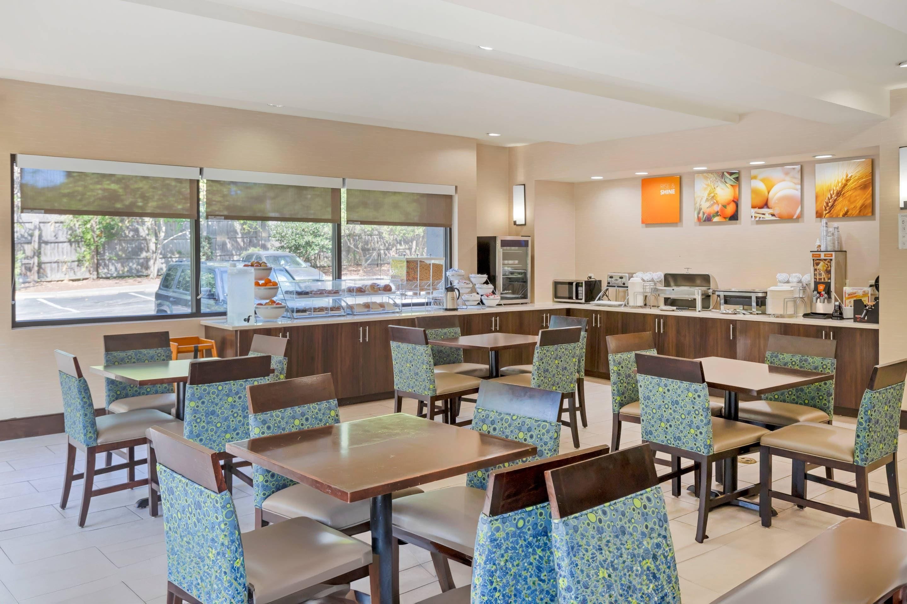 A restaurant with booths and tables, a kitchen area, and large windows with a view of the outside.