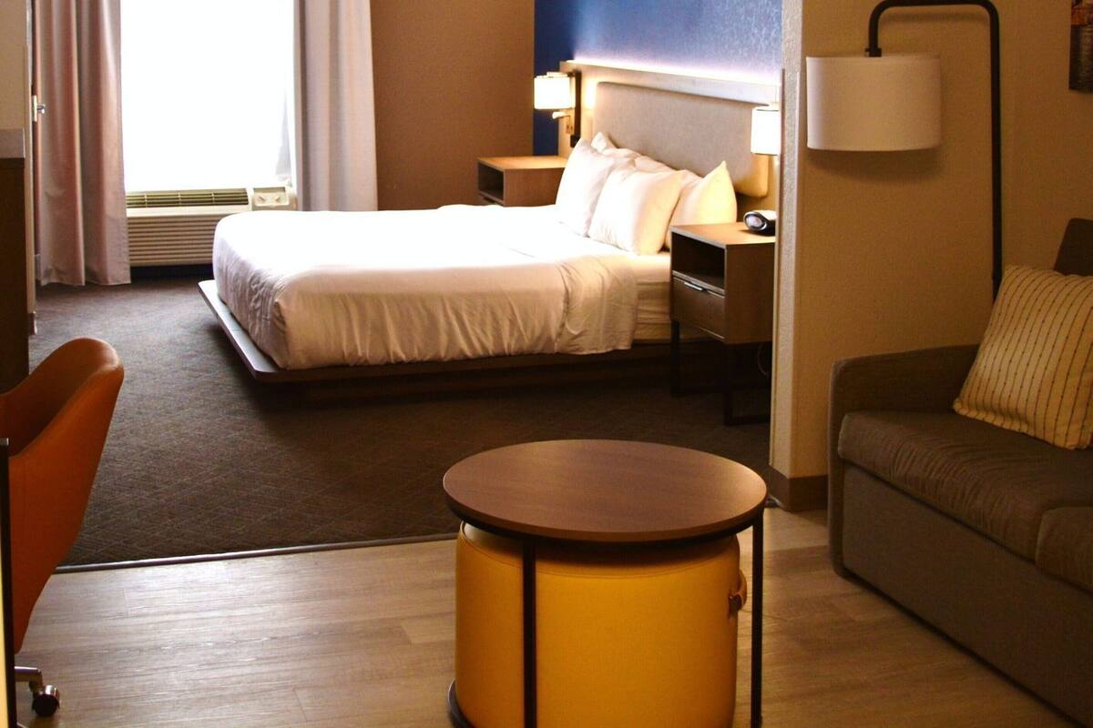 Une chambre d’hôtel comprenant un lit, un bureau, une chaise, un canapé et une lampe.