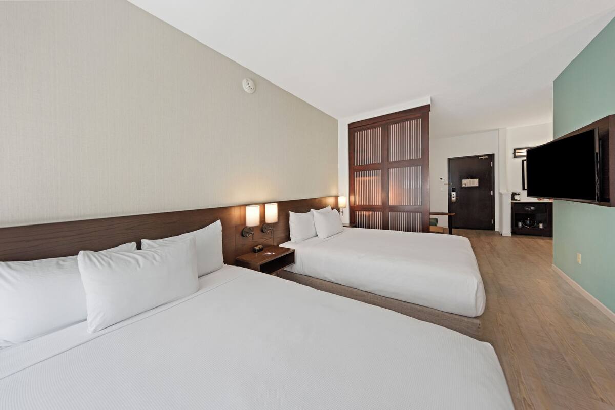 A hotel room with two beds, a TV, a desk, and a wardrobe.
