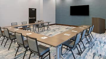 A conference room with a long table, chairs, a TV, and a door.