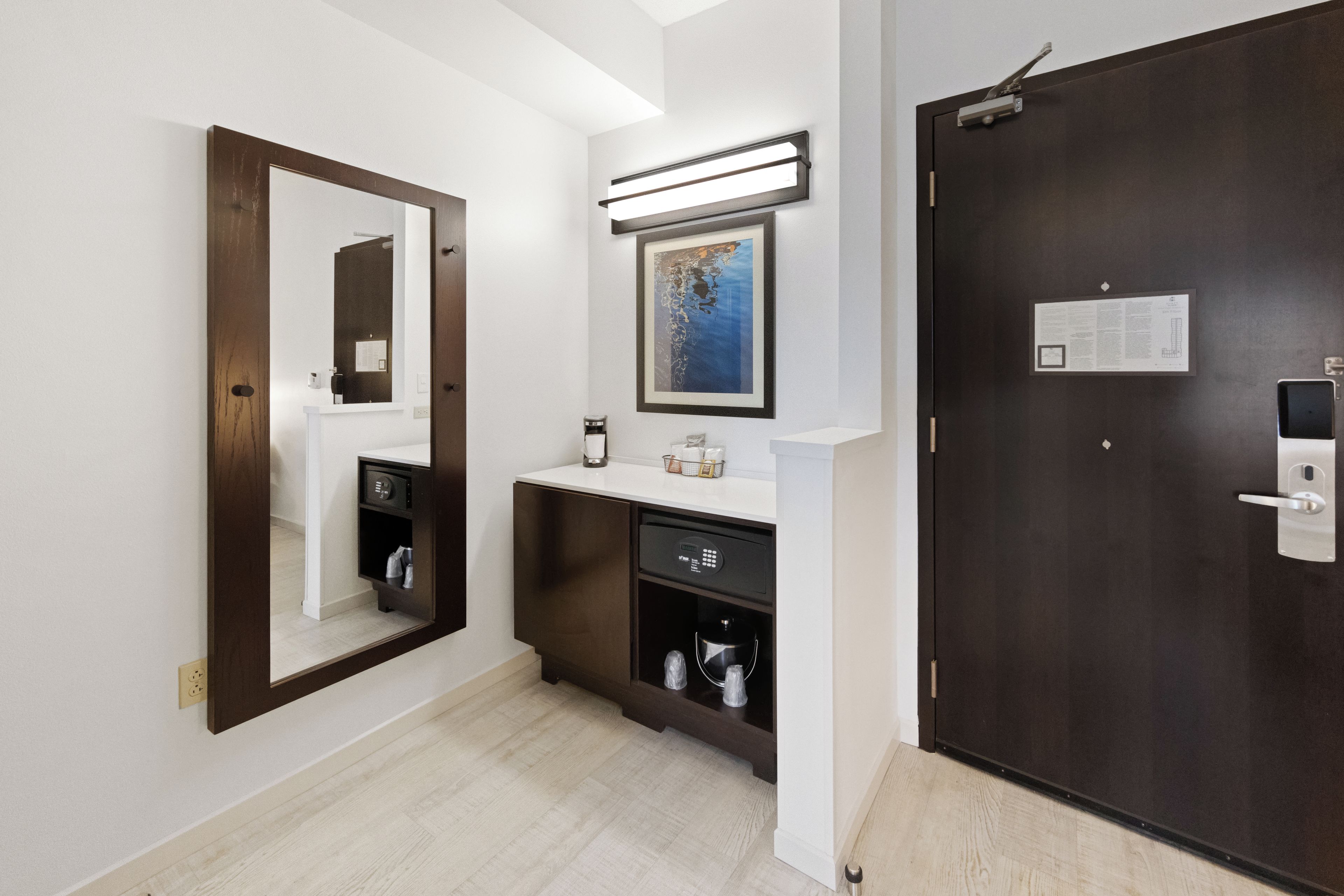 Une salle de bain moderne avec un grand miroir, un lavabo doté d’un plan de travail et une porte sombre.