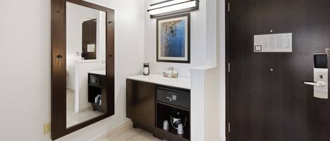 Une salle de bain moderne avec un grand miroir, un lavabo doté d’un plan de travail et une porte sombre.