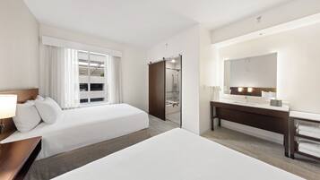 A hotel room with two beds, a bathroom, and a large mirror.