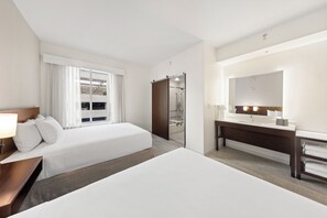 Una habitación de hotel con dos camas, un baño y un espejo grande.
