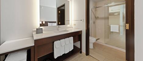 A modern bathroom with a large mirror, white sink, and wooden vanity.