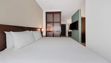 A hotel room with a large bed, a TV, and a sliding door leading to a bathroom.