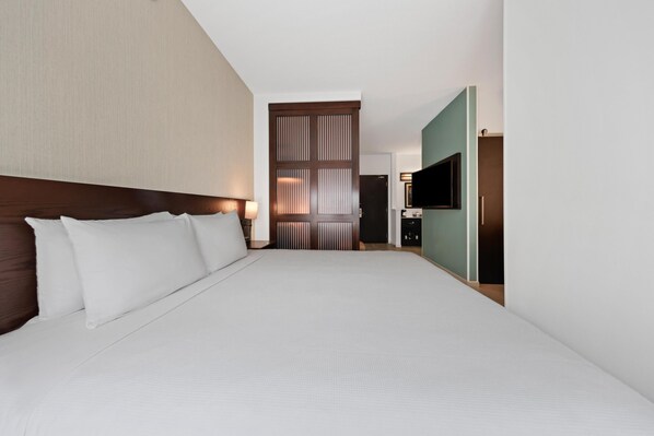 A hotel room with a large bed, a TV, and a sliding door leading to a bathroom.