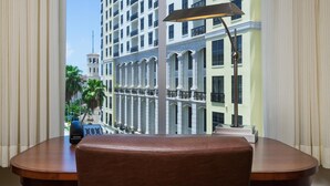 A hotel room with a view of a multi-story building, a desk with a lamp, and a telephone. - Hyatt Place West Palm Beach/Downtown (West Palm Beach)