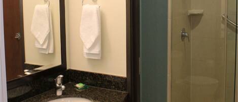 Une salle de bain équipée d’un lavabo, d’un miroir, d’un porte-serviettes et d’une douche à parois de verre.