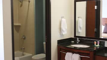 Un baño con bañera, inodoro, lavamanos y un espejo grande.