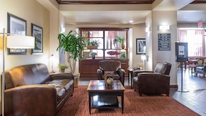 A lobby with leather sofas, a coffee table, potted plants, and a reception desk.