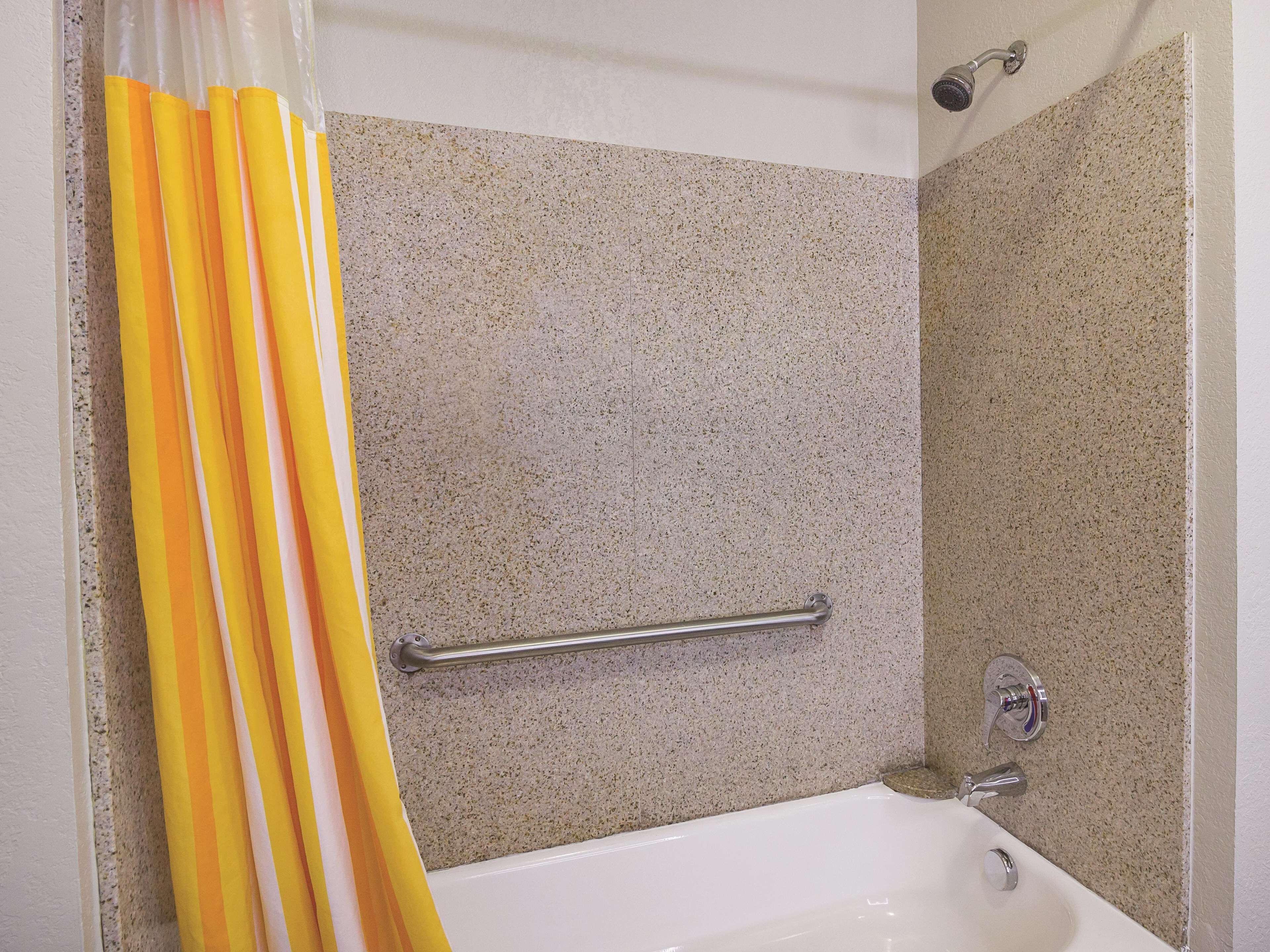 A bathroom with a bathtub, a shower, and a handrail.