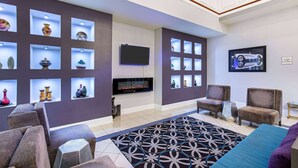 Een moderne woonkamer met banken, een flatscreen televisie, decoratieve vazen en een kamerkleed met een patroon.