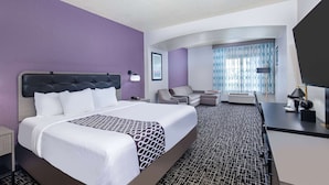 Een hotelkamer met een groot bed, een bureau, een stoel en een televisie.