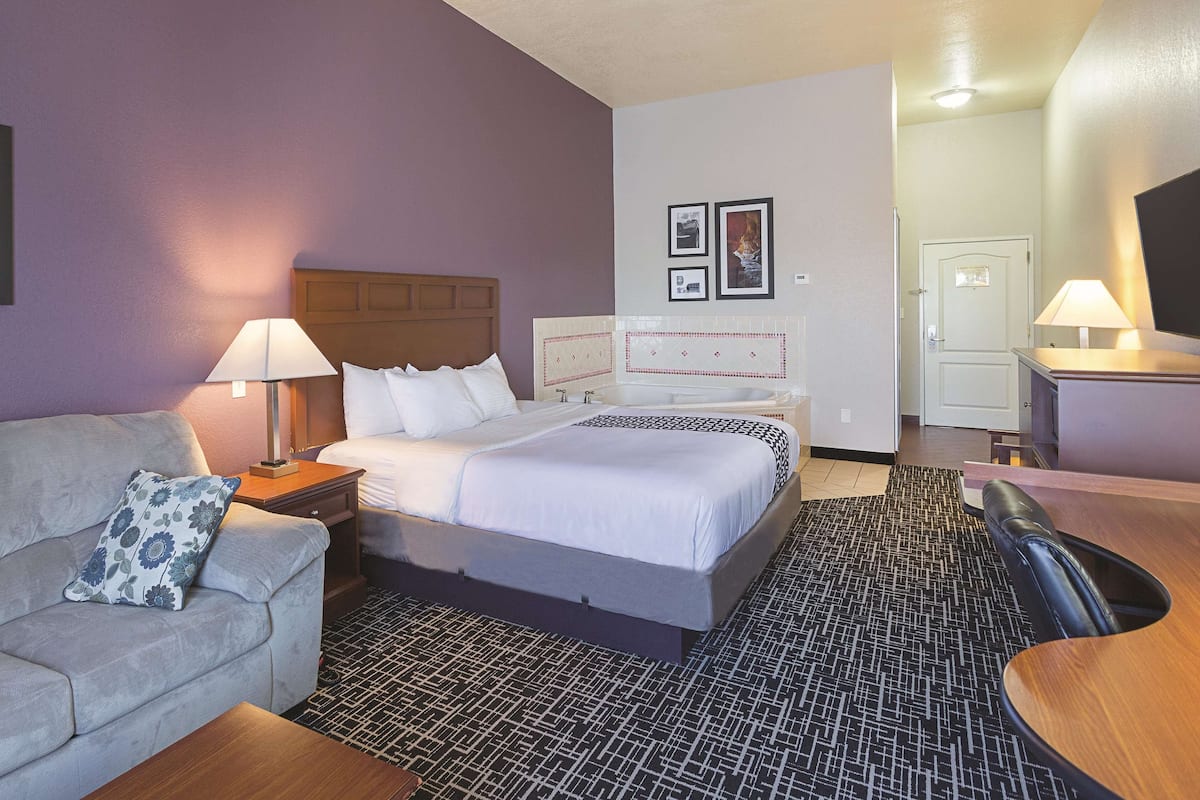 A hotel room with a bed, a sofa, a desk, and a television.