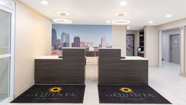A reception area with two dark reception desks, a cityscape mural on the wall, and a door to the right.