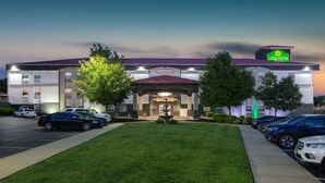 A La Quinta hotel with a parking lot, a fountain, and a well-maintained lawn.