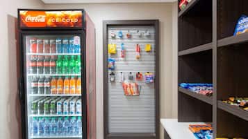 A vending machine with various drinks and snacks, a closed snack bar, and shelves with packaged goods.