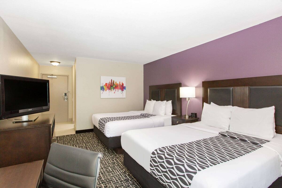 Habitación de hotel con dos camas, televisión, escritorio y una silla.