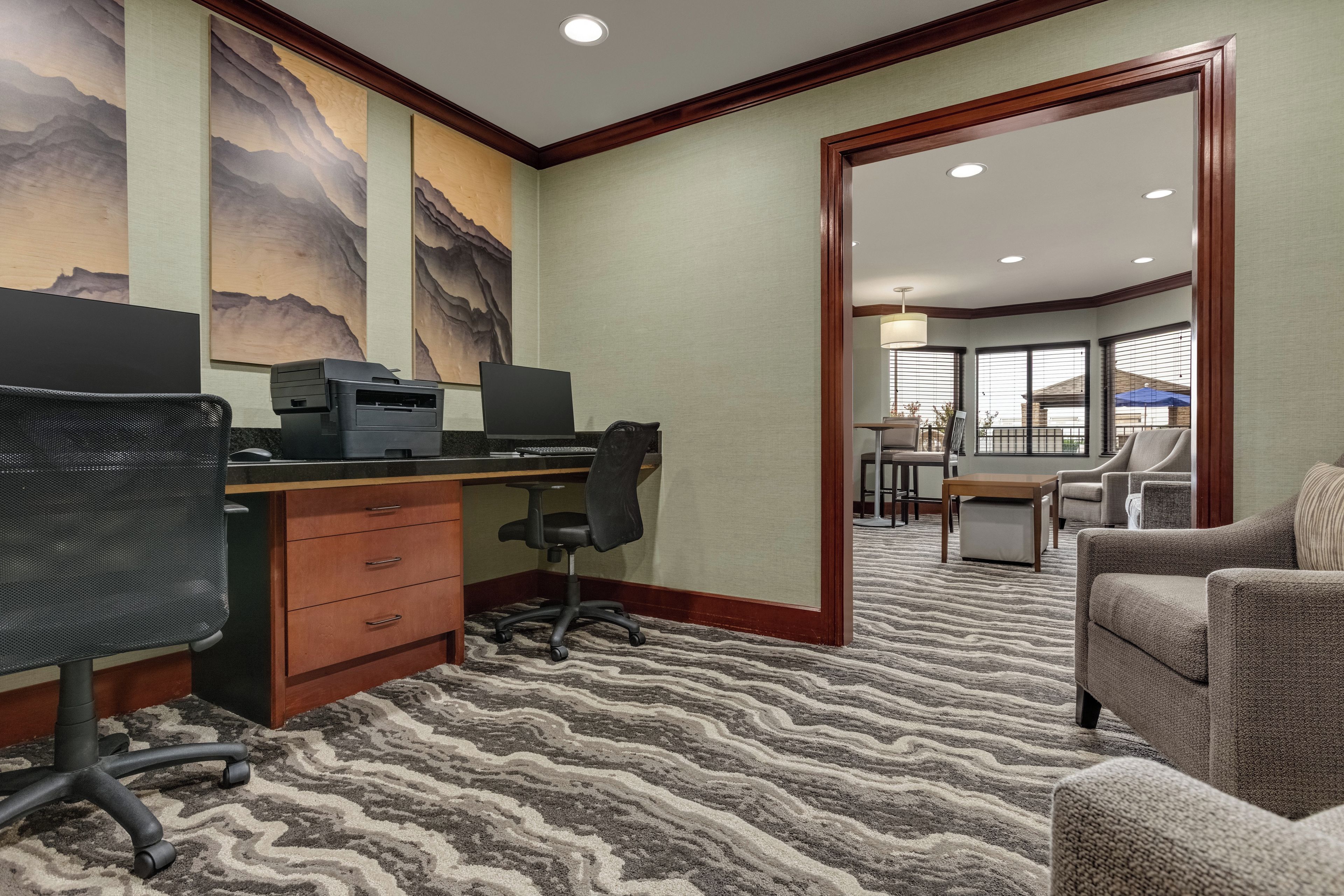 Une chambre d’hôtel équipée d’un bureau, d’un fauteuil de bureau et d’une grande fenêtre.